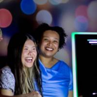Three grads laugh taking photo at photo booth